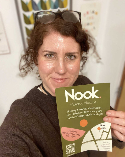 Emma from every nook holding a green 'Nook' flyer with a map on a white wall background